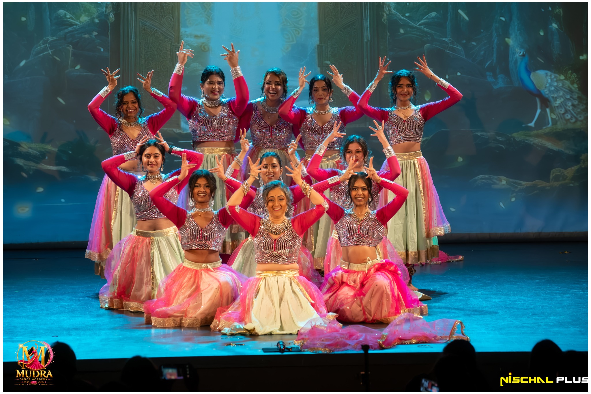 Mudra Dance Academy dancers in pink and yellow costumes in a stage formation