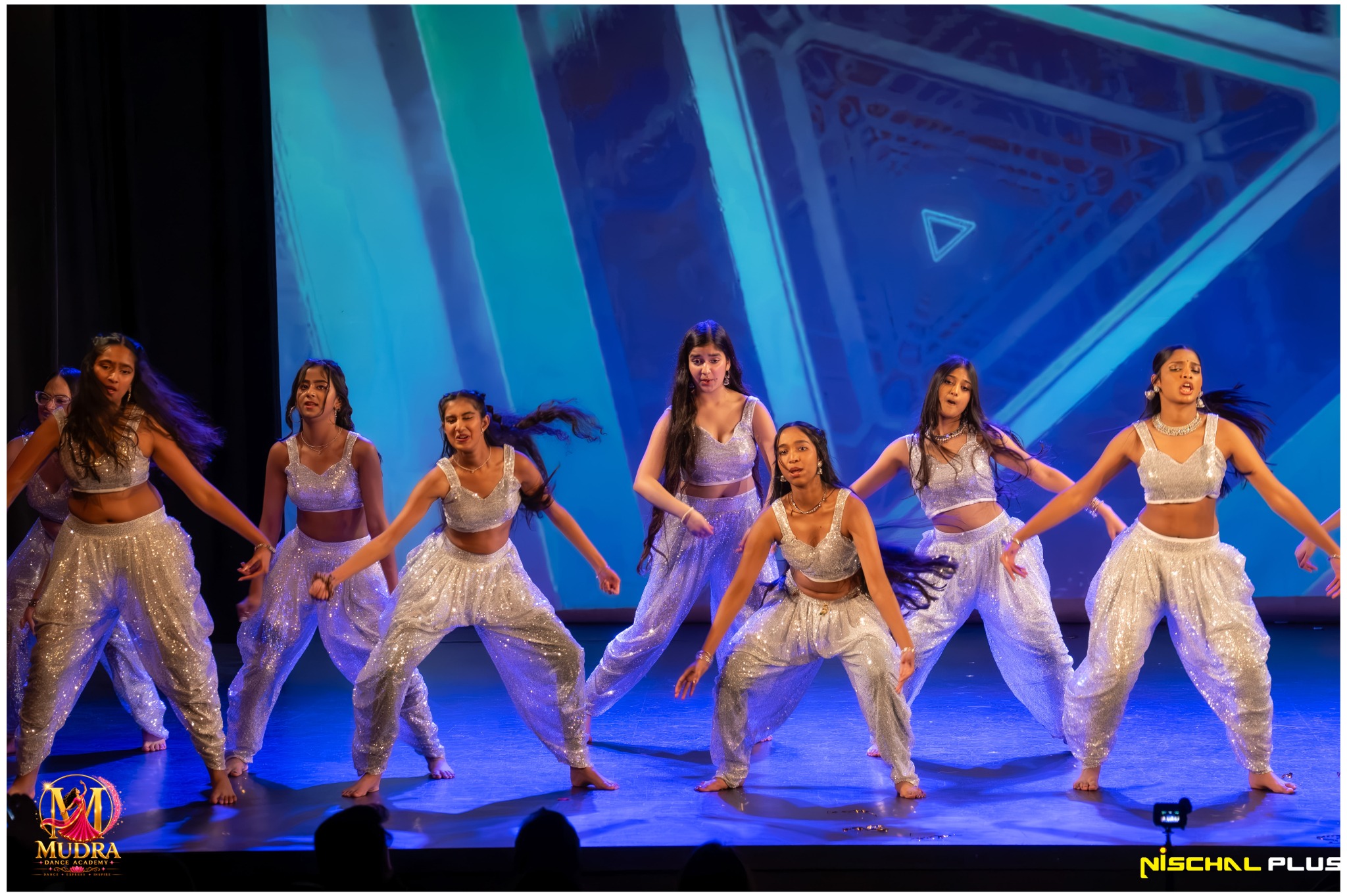 Mudra Dance Academy dancers performing an energetic silver-costume routine